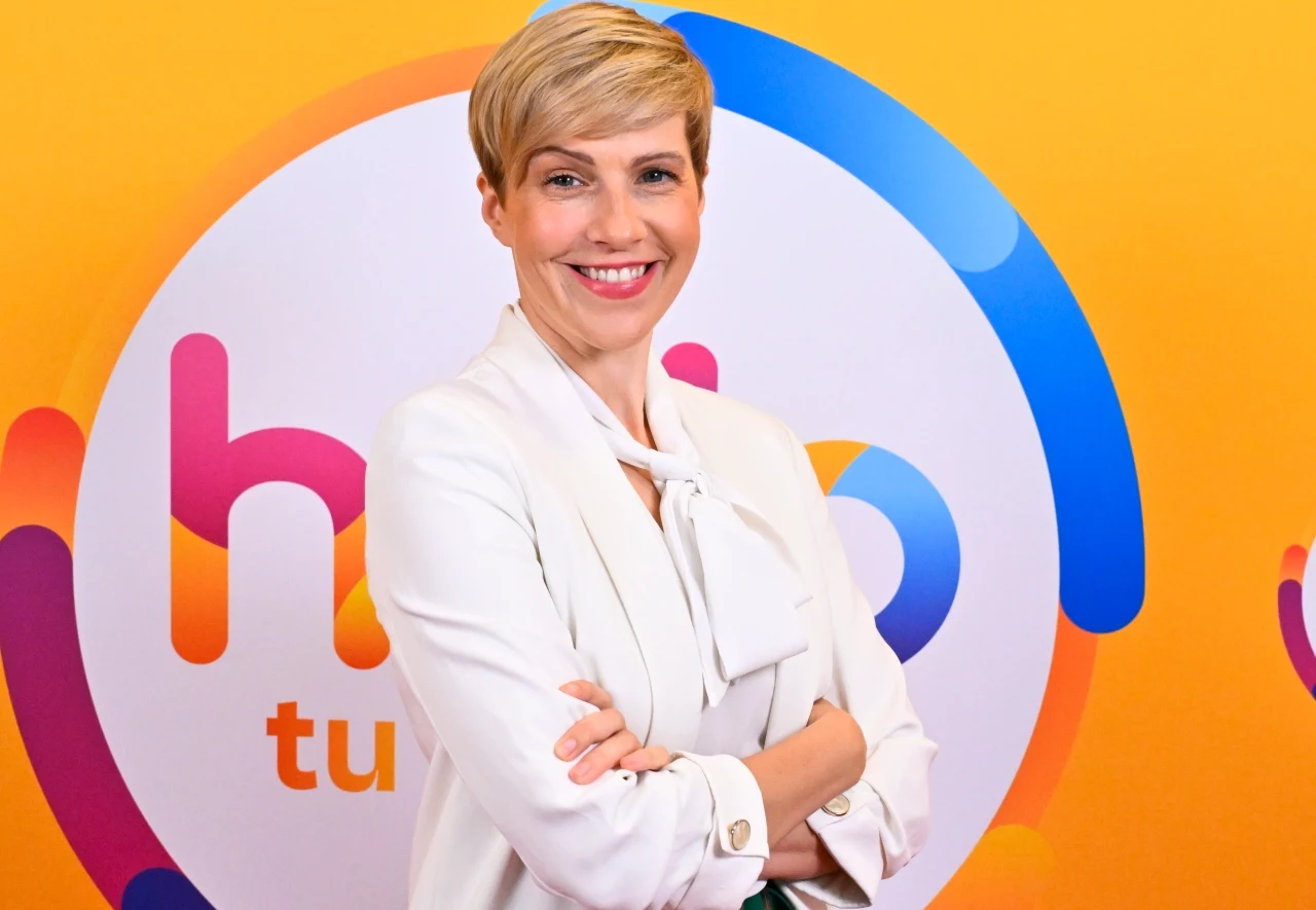 Dietetyczka Magdalena Czyrynda-Koleda Dietetyczka Magdalena Czyrynda-Koleda w białej marynarce na tle kolorowego logotypu „halo” w studiu Polsat.