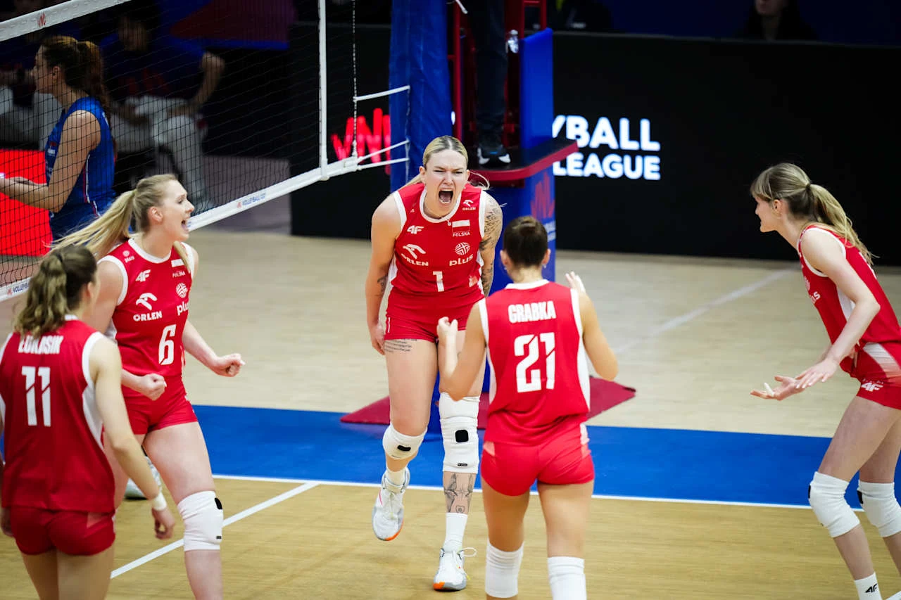Julia Szczurowska (z numerem 1) w siatkarskiej reprezentacji Polski Grupa siatkarek w czerwonych strojach energicznie świętuje udaną akcję na boisku, jedna z zawodniczek wyraża silne emocje, a pozostałe kierują się w jej stronę z uniesionymi rękami.