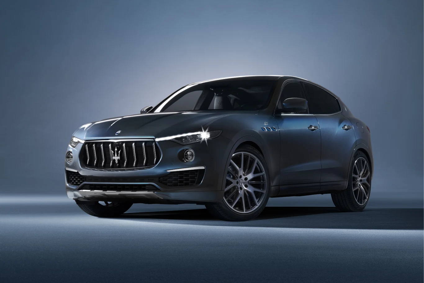 Luksusowy SUV Maserati Levante w ciemnoszarym kolorze z charakterystycznym grillem, wyrazistymi reflektorami LED i dużymi aluminiowymi felgami na jednolitym tle.