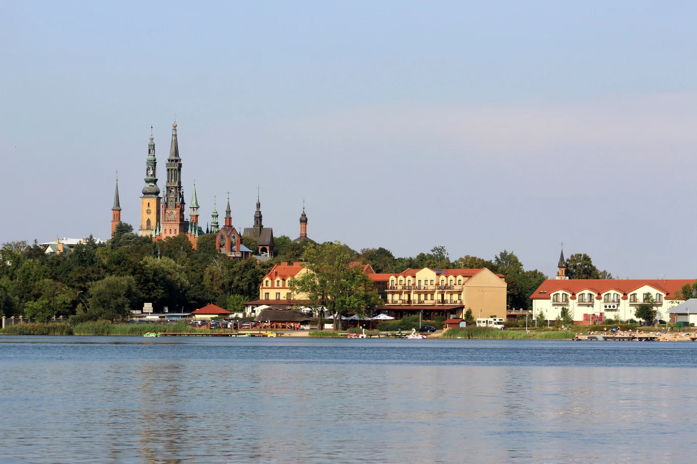 Malownicza panorama miasta z charakterystycznymi wieżami dużej bazyliki górującej nad zabudową i brzegiem jeziora.