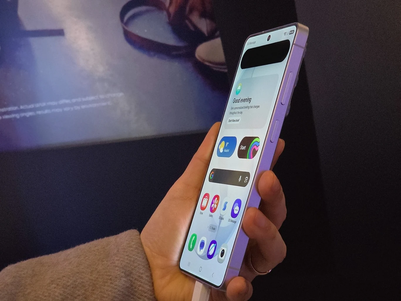 Jak AI zmienia urządzenia mobilne i jakie kierunki rozwoju technologii można przewidywać w najbliższych latach? Osoba trzyma fioletowy smartfon z dużym ekranem, wyświetlającym aplikacje i widżety w przejrzystym układzie.