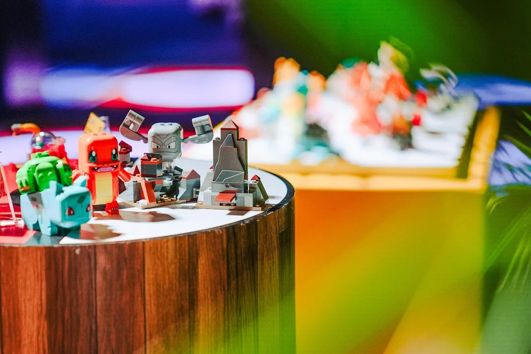 Świat Pokemonów daje ogromne pole do rozbudowy całej serii Klockowe figurki znanych postaci z gier komputerowych ustawione na okrągłym, drewnianym stoliku na kolorowo oświetlonym tle.