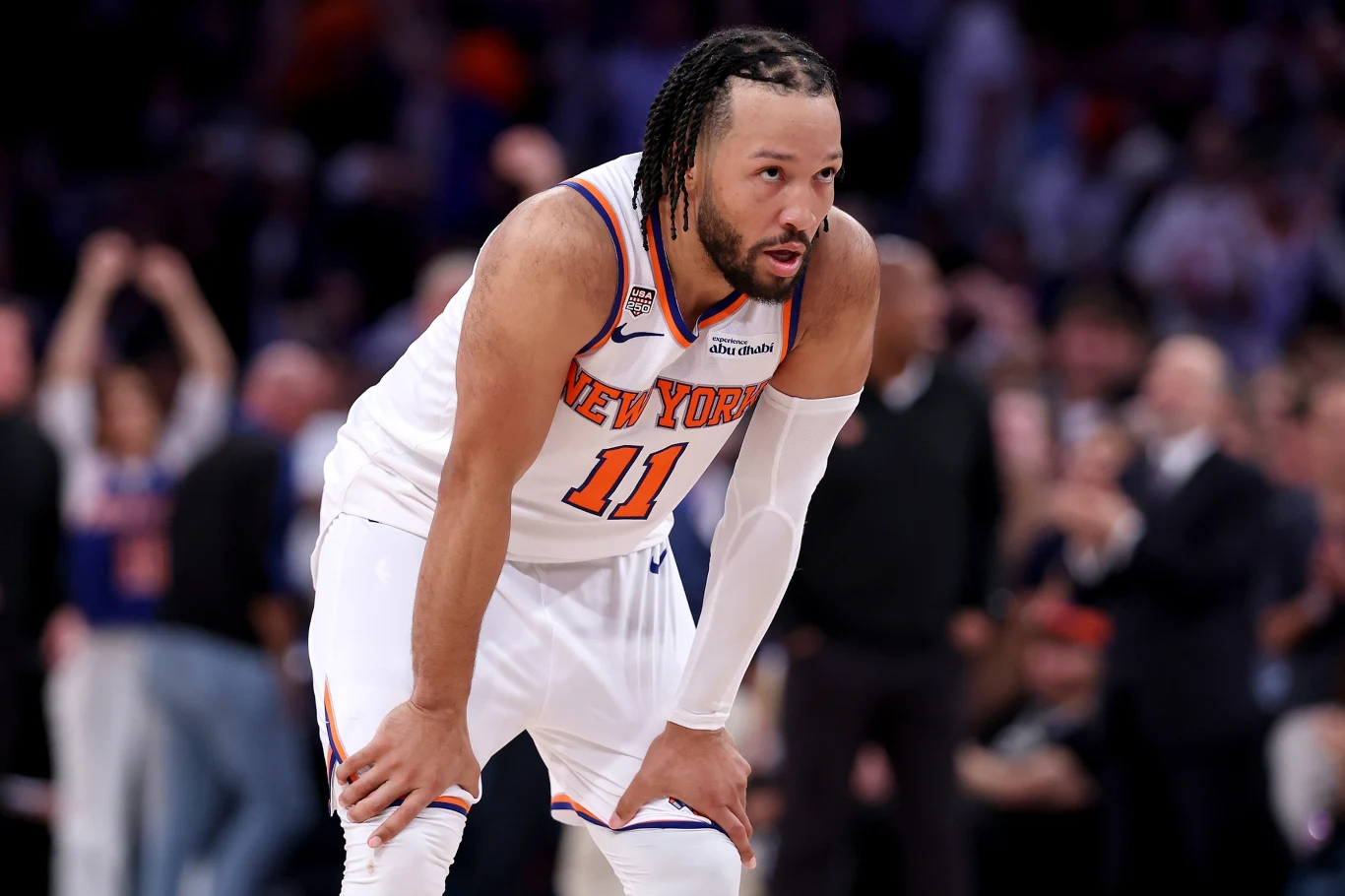 Jalen Brunson Koszykarz drużyny New York Knicks w białym stroju z numerem 11 stoi pochylony z rękami opartymi na kolanach podczas meczu.
