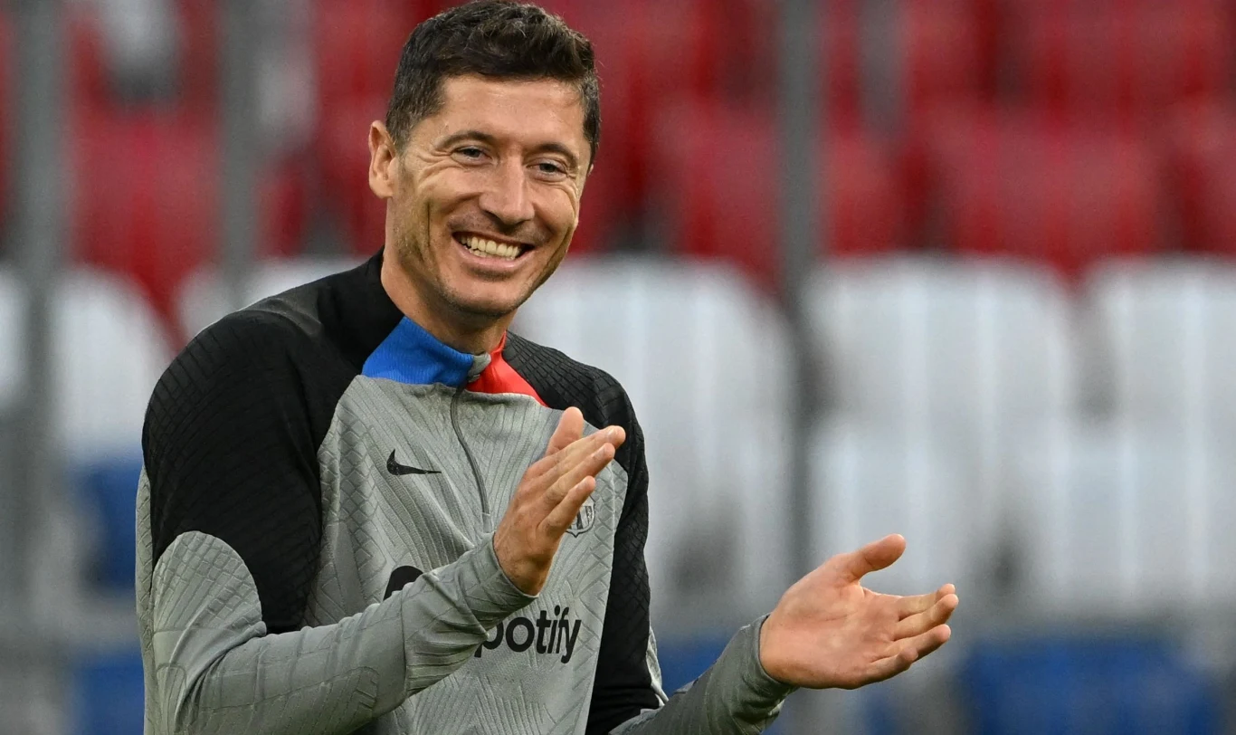 Robert Lewandowski Uśmiechnięty mężczyzna w sportowej bluzie z logo Spotify klaszcze w dłonie, stojąc na tle stadionowych trybun.