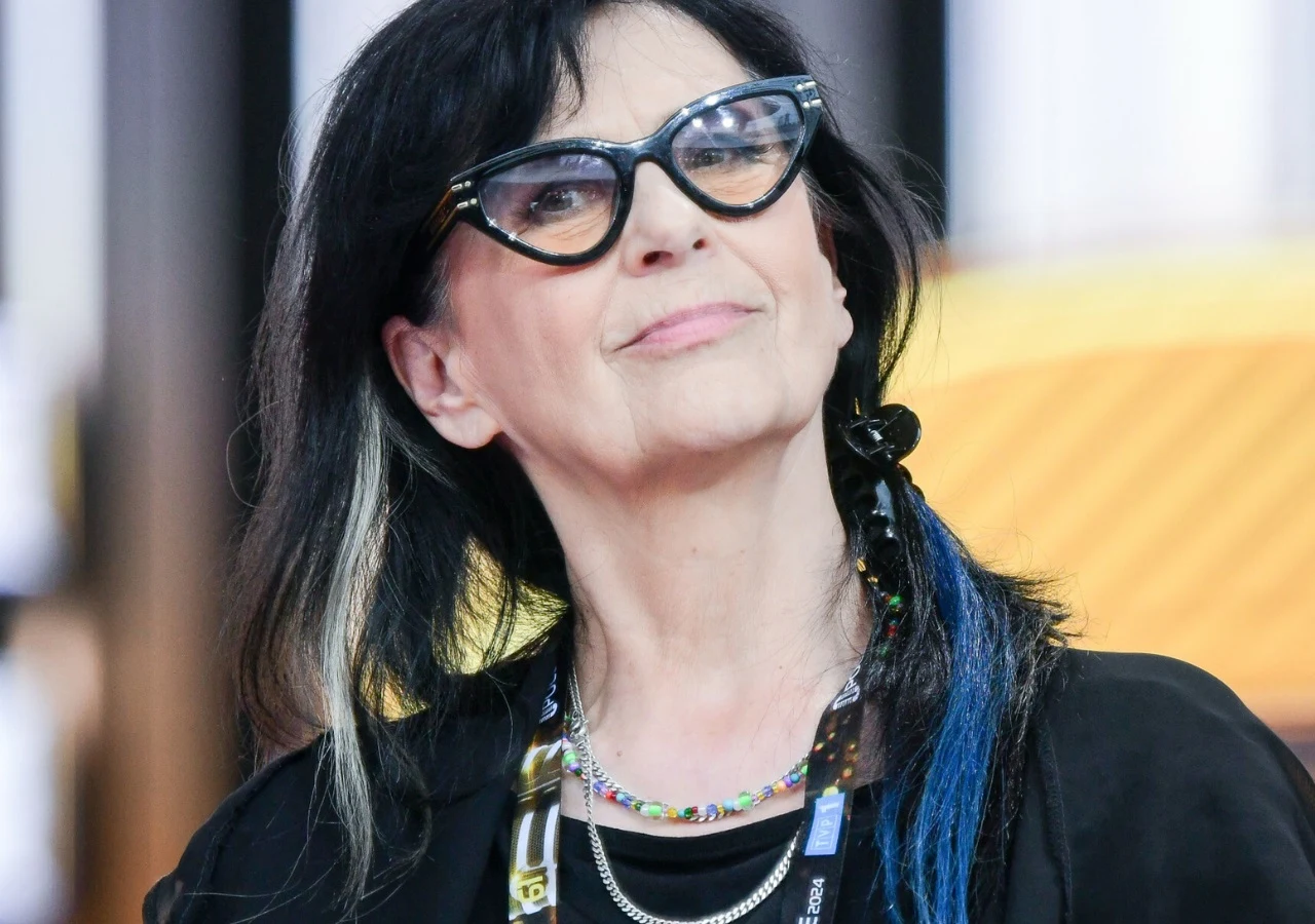 Wanda Kwietniewska Wanda Kwietniewska w czarnej bluzce, charakterystycznych okularach i naszyjniku, z włosami w kolorowych pasmach.