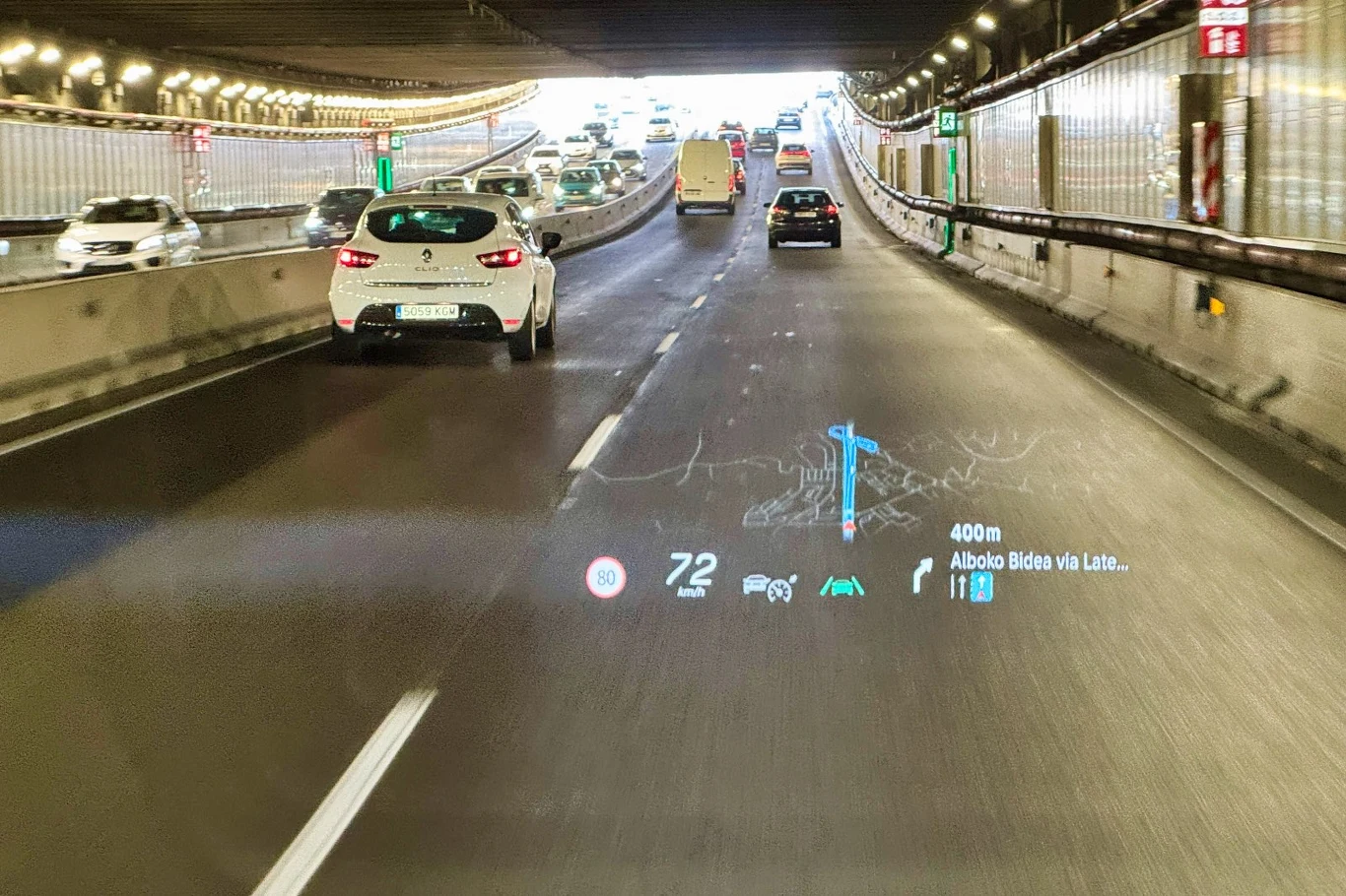HUD daje kierowcy dostęp do danych gdy patrzy na drogę Samochody poruszające się wielopasmową drogą w tunelu, na przedniej szybie wyświetlają się cyfrowe informacje nawigacyjne i prędkość pojazdu.