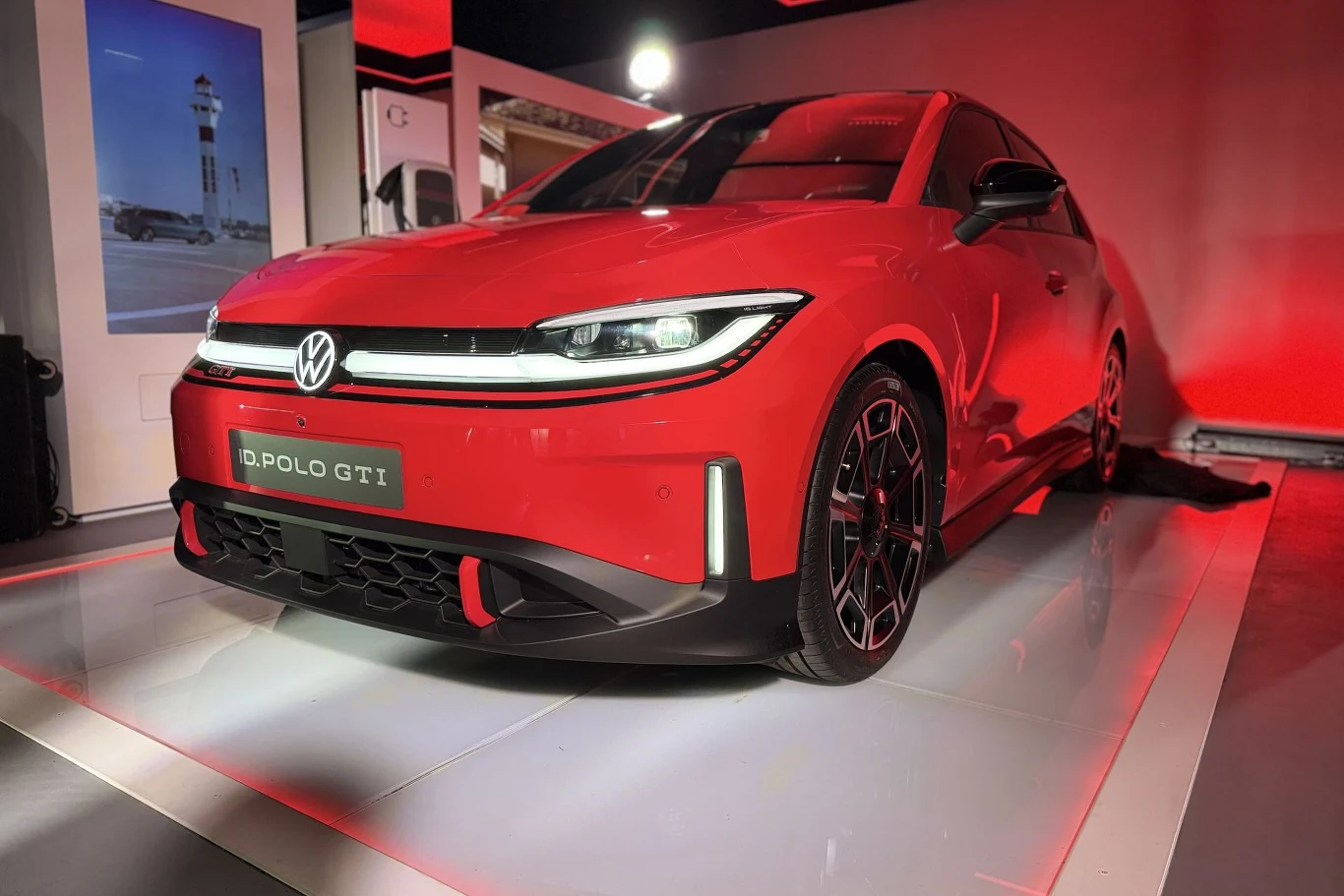 Volkswagen ID.Polo GTI to pierwsze GTI zasilane prądem. Czerwony Volkswagen ID.Polo GTI na ekspozycji w podświetlonym na czerwono wnętrzu, widoczne LED i felgi.