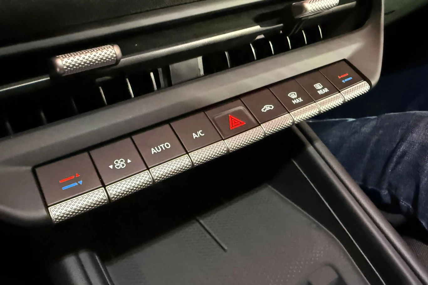Podobnie jak w "zwykłym" ID.Polo, w ID.Polo GTI znajdziemy fizyczne przełączniki do sterowania klimatyzacją. Panel sterowania klimatyzacją w samochodzie z przyciskami do regulacji nawiewu, temperatury, trybu automatycznego, klimatyzacji, świateł awaryjnych i wentylacji przedniej oraz tylnej szyby.