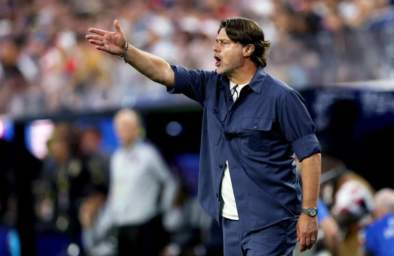 Mauricio Pochettino podczas meczu USA - Paragwaj Mężczyzna w granatowym stroju energicznie gestykuluje i wydaje polecenia, stojąc na tle rozmytego tłumu podczas wydarzenia sportowego.
