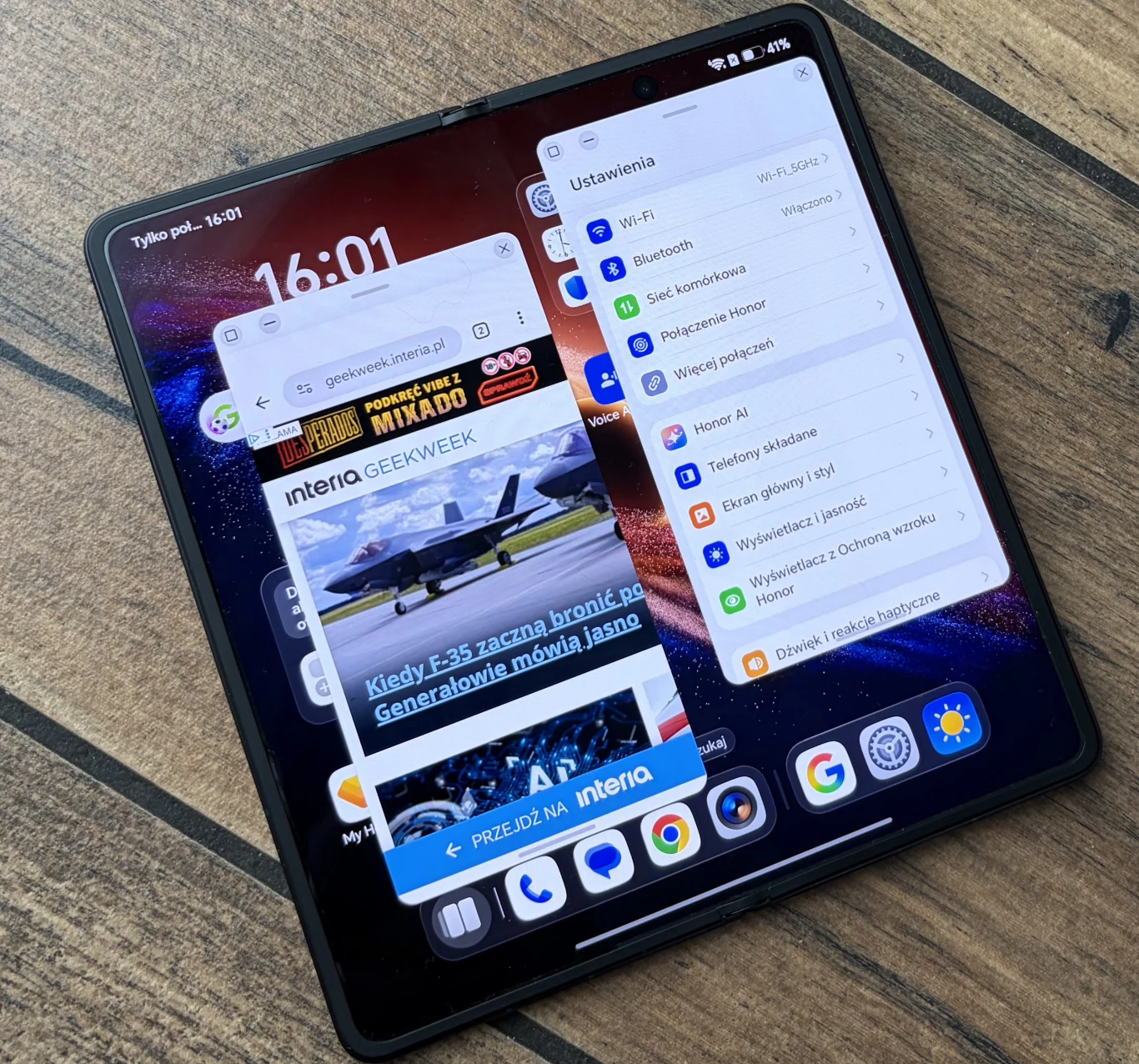 Rozłożony smartfon z dużym ekranem dotykowym, na którym wyświetlone są jednocześnie okno przeglądarki internetowej oraz panel ustawień systemowych, z widocznymi ikonami popularnych aplikacji na dolnym pasku.