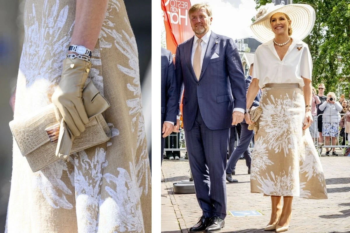 Elegancka kobieta w białej bluzce i długiej, beżowej spódnicy z białym wzorem kwiatowym oraz dużym kapeluszu, trzyma beżową kopertówkę i nosi jasne rękawiczki, idzie obok elegancko ubranego mężczyzny w granatowym garniturze, oboje uśmiechnięci w przest...