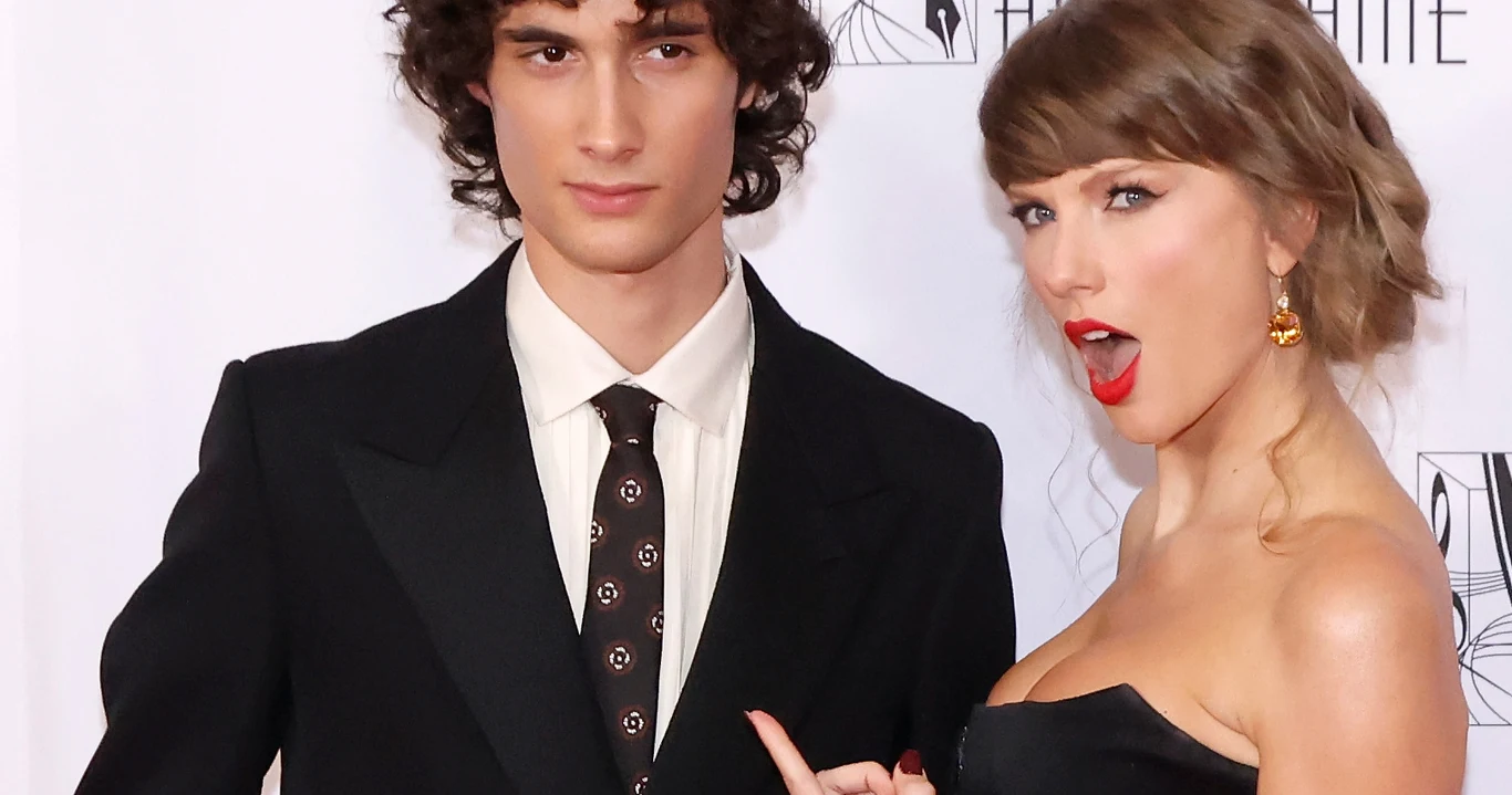 Taylor Swift publicznie pochwaliła młodego wokalistę. Kim jest? Elegancko ubrany mężczyzna w ciemnym garniturze i kobieta w czarnej sukni wskazująca na niego.