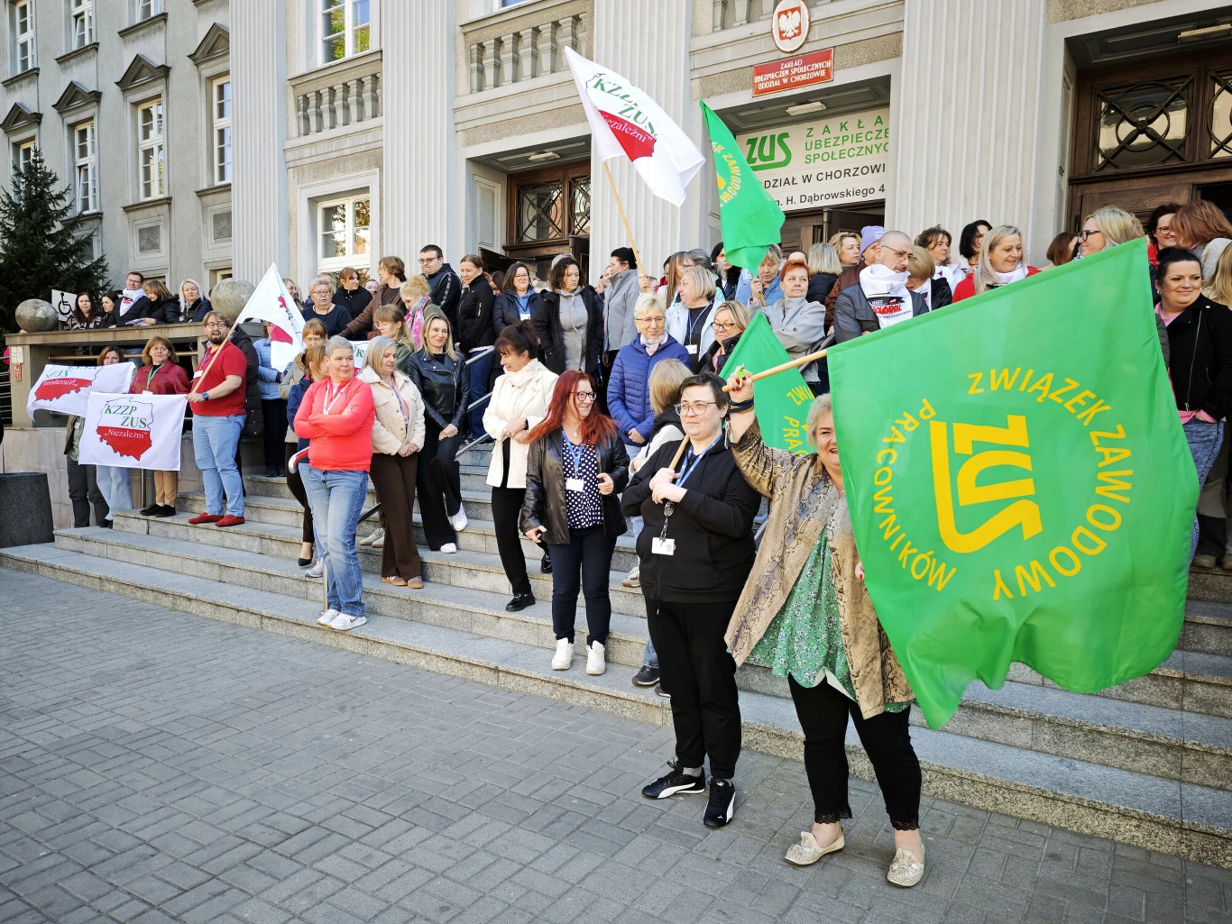 Pod koniec kwietnia pod siedzibą resortu finansów odbyła się demonstracja pracowników ZUS Demonstracja pracowników ZUS na schodach przed resortem finansów, widoczne flagi związków zawodowych.