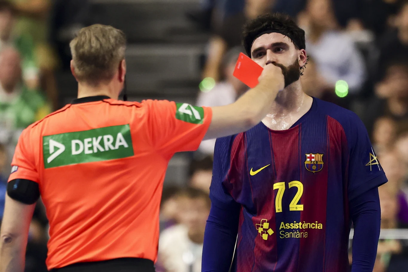 Sędzia w pomarańczowej koszulce pokazuje czerwoną kartkę zawodnikowi drużyny FC Barcelona w granatowo-bordowym stroju z numerem 72.