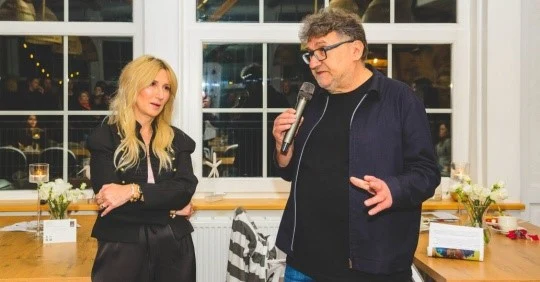 Agnieszka Będkowska, dyrektorka Wytwórni Filmów Fabularnych i Dokumentalnych i Jerzy Kapuściński, dyrektor artystyczny Studia Munka SFP Mężczyzna z mikrofonem przemawia do kobiety stojącej obok, oboje znajdują się przy stole ozdobionym kwiatami i świecami, w tle widoczne duże okna oraz uczestnicy spotkania.