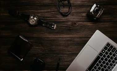 Męskie akcesoria na drewnianym biurku — zegarek, portfel, perfumy i laptop jako prezent na Dzień Ojca