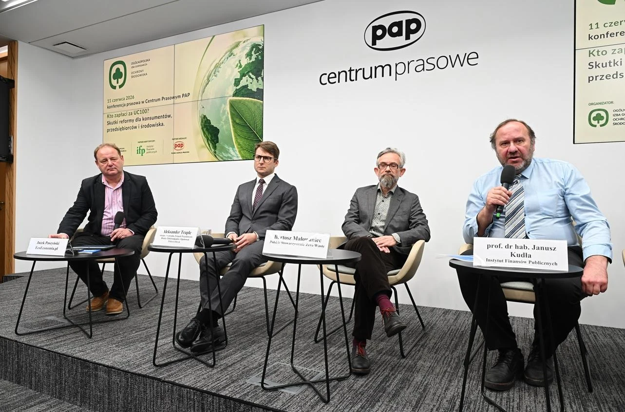 Czterech mężczyzn siedzących przy stole na scenie podczas konferencji prasowej, każdy z mikrofonem lub notatkami, na tle baneru z logo oraz napisem 'PAP centrum prasowe'.
