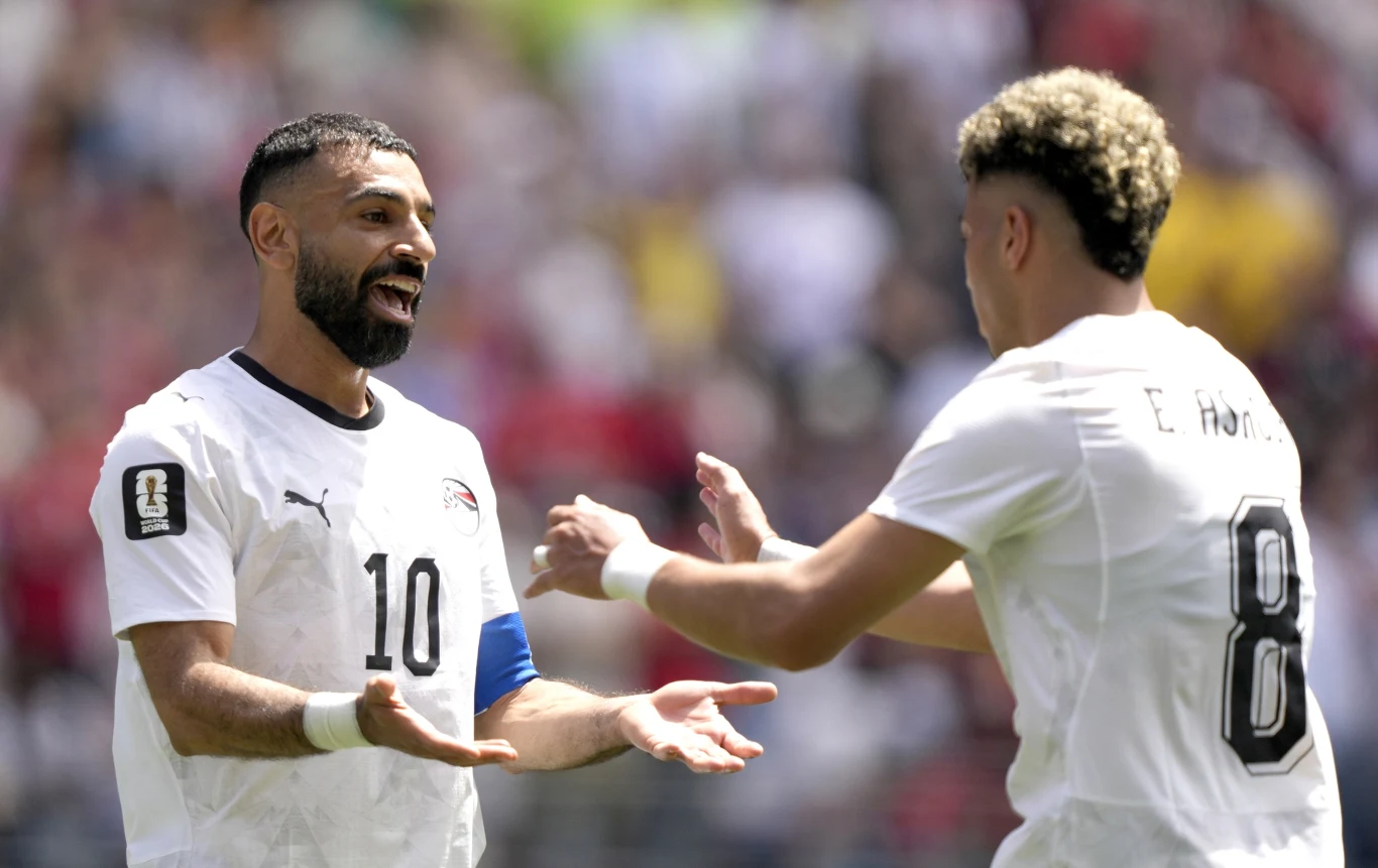Mohamed Salah (z lewej) tym razem wcielił się w rolę asystenta Dwóch piłkarzy w białych koszulkach, z numerami 10 i 8, wymienia gesty radości na boisku podczas meczu.