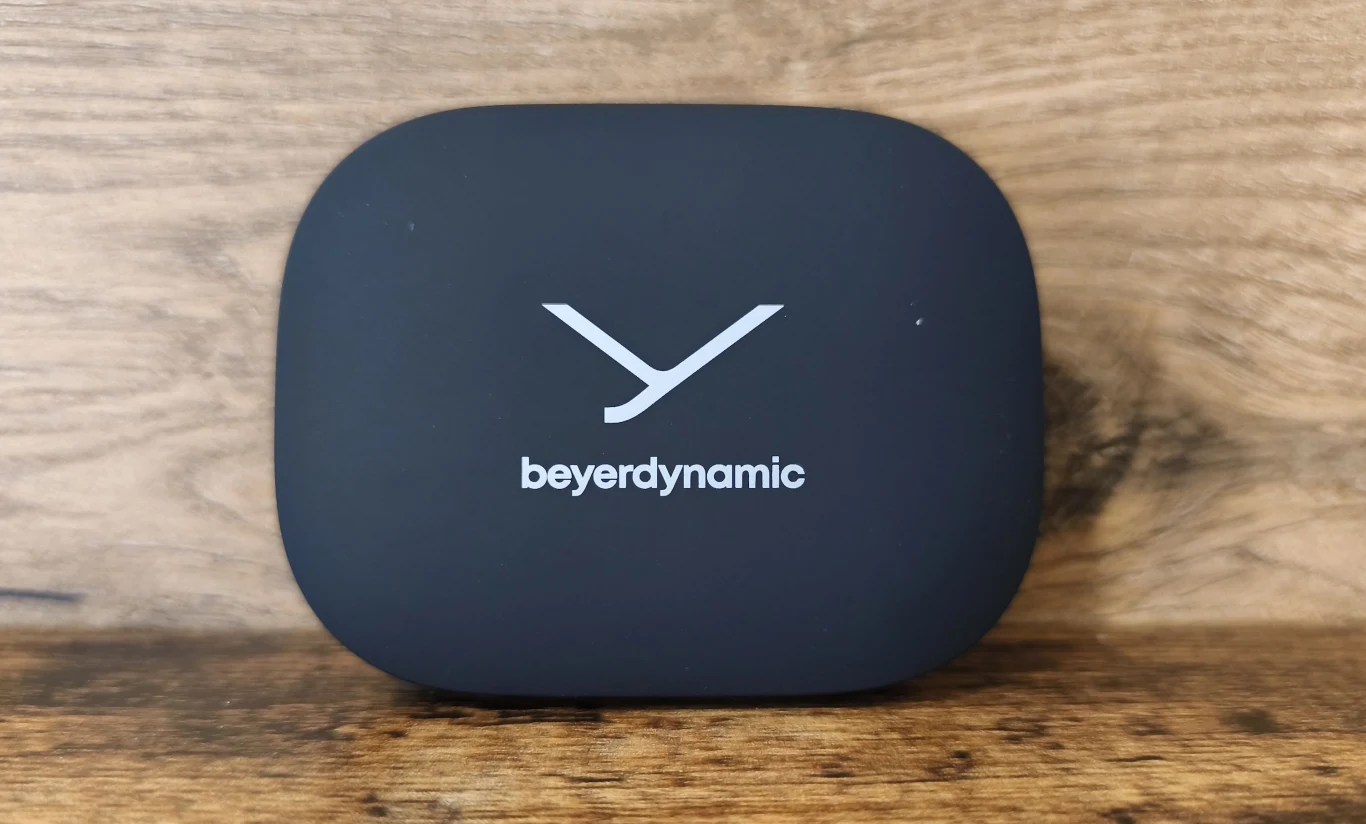 Czarne, matowe etui z białym logo i nazwą marki beyerdynamic, ustawione na drewnianej powierzchni.