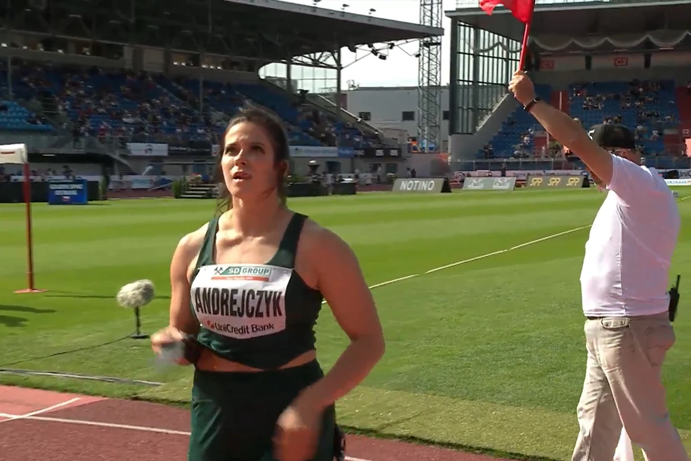 Maria Andrejczyk w Ostrawie po spalonej próbie Zawodniczka w stroju sportowym z numerem startowym na piersi na stadionie lekkoatletycznym, w tle sędzia unoszący czerwoną flagę i trybuny z widownią.