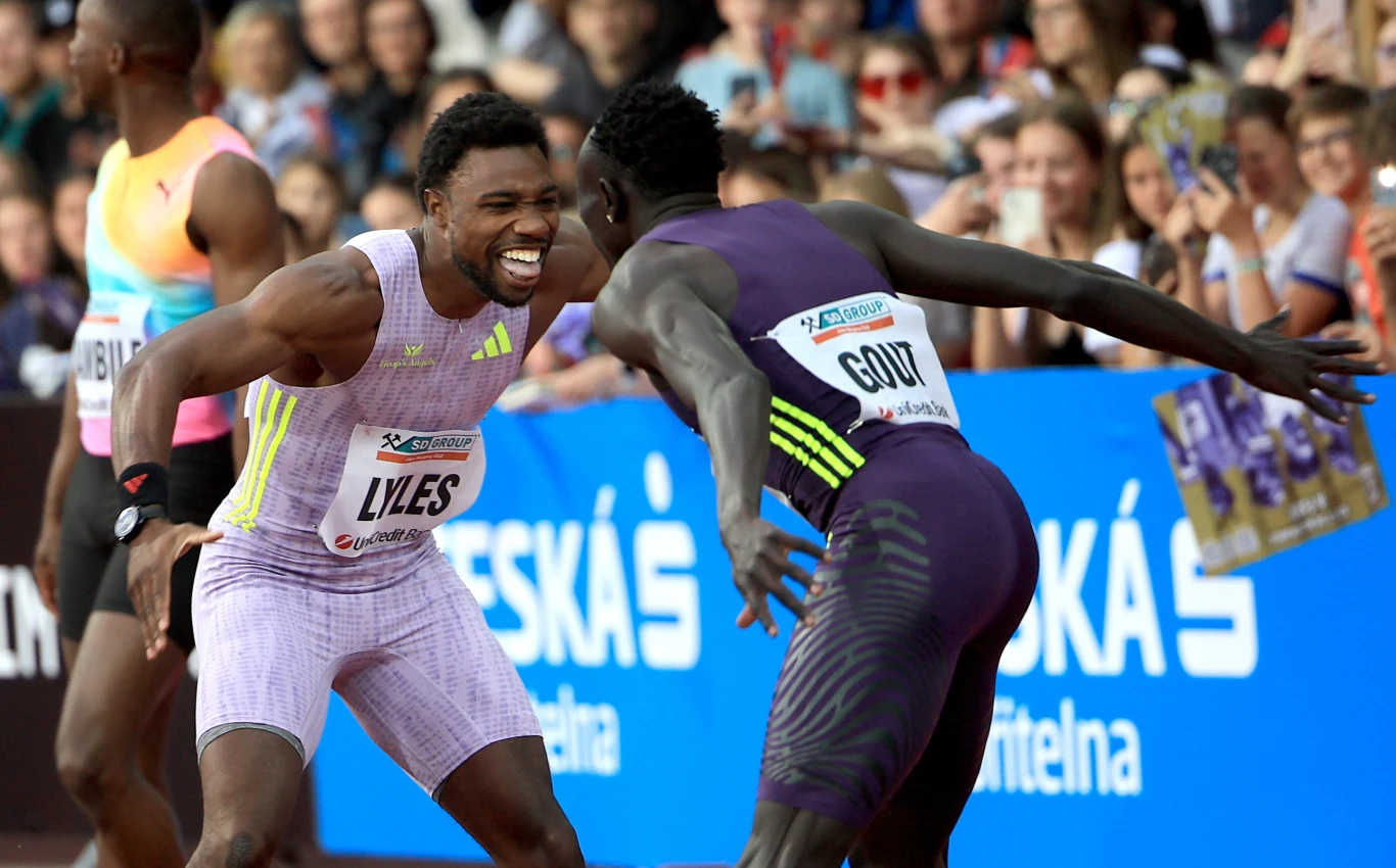 Noah Lyles i Gout Gout tuż po biegu Dwóch lekkoatletów w sportowych strojach świętuje sukces na bieżni, w tle widoczna zadowolona publiczność oraz reklamy sponsorskie.