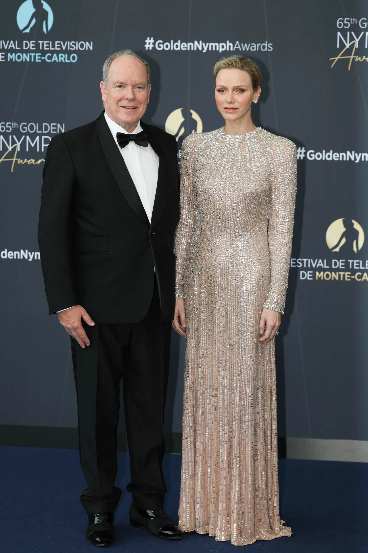 Elegancko ubrana para w wieczorowych strojach pozuje na tle ścianki z logo Festiwalu Telewizyjnego w Monte-Carlo i napisami związanymi z galą Golden Nymph Awards.
