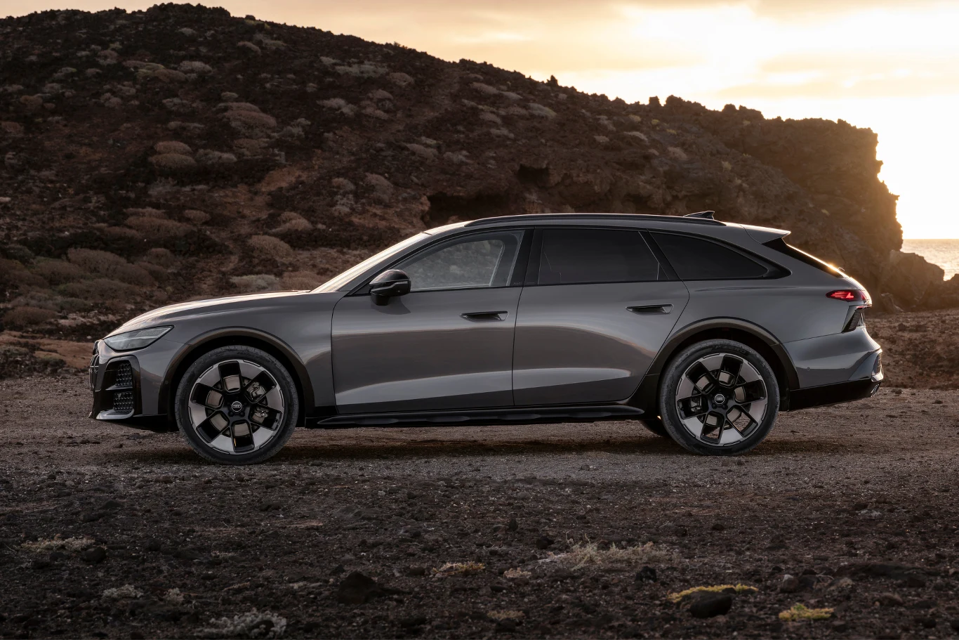 Audi A6 allroad ma nieco ponad 5 m długości. Srebrny samochód kombi o sportowym charakterze zaparkowany na kamienistym terenie, w otoczeniu skał i pod zachmurzonym niebem.