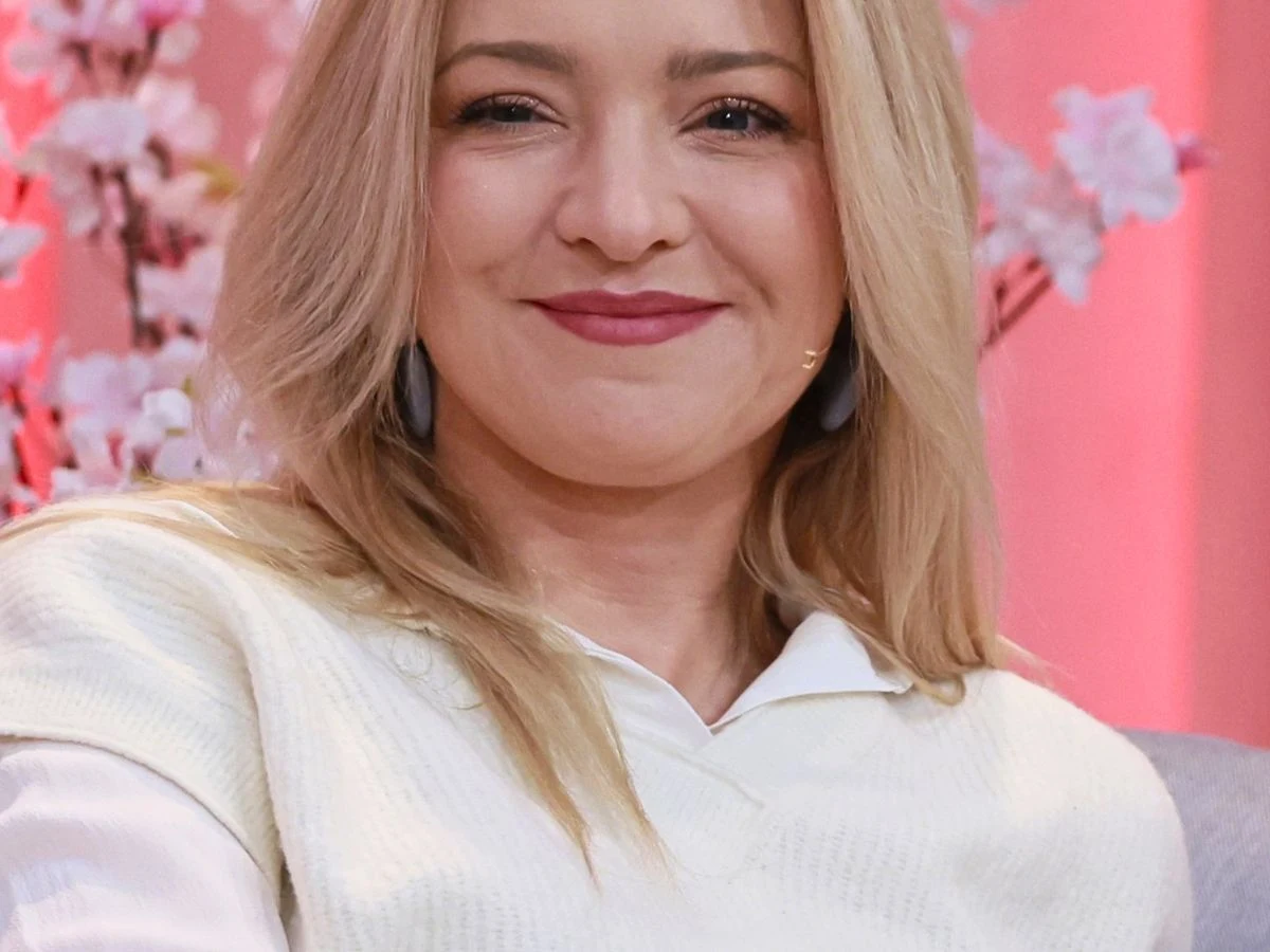 Barbara Kurdej-Szatan Uśmiechnięta Barbara Kurdej-Szatan na tle ozdobnych, pastelowych gałązek kwiatowych.