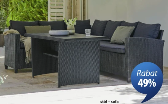 zestaw ogrodowy AGERMOSE (stół i sofa) za 1500 zł Czarna sofa z poduchami i dopasowany stół z technorattanu, ustawione na tarasie, ozdobione jasną rośliną w doniczce oraz szklanką i misą.
