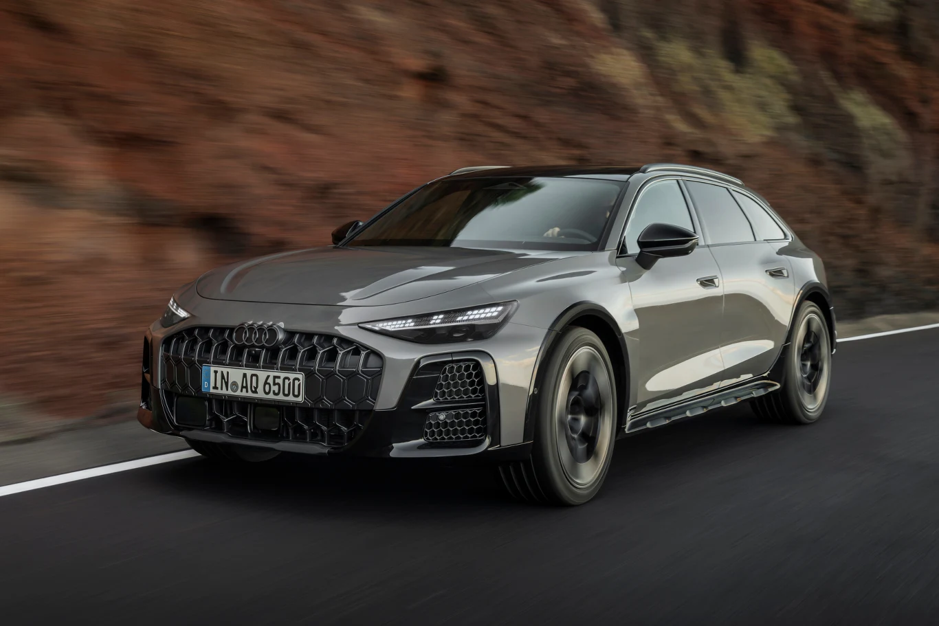 Audi chwali się, że najnowsze wcielenie A6 allroad jest najbardziej aerodynamicznym kombi ze spalinowym silnikiem w historii. Srebrne Audi jadące dynamicznie pustą, asfaltową drogą przy skalistej ścianie.