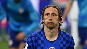 Piłkarz w niebieskiej koszulce reprezentacji Chorwacji z widoczną flagą na piersi, z poważnym wyrazem twarzy, podczas meczu piłkarskiego.
