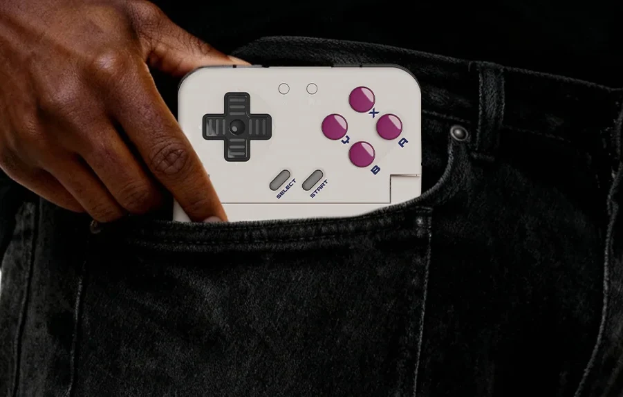 Powstał Game Boy dla współczesnych graczy. Wystarczy wsunąć do niego telefon Ręka wsuwająca kontroler Pocket Taco z widocznymi przyciskami do kieszeni czarnych spodni.
