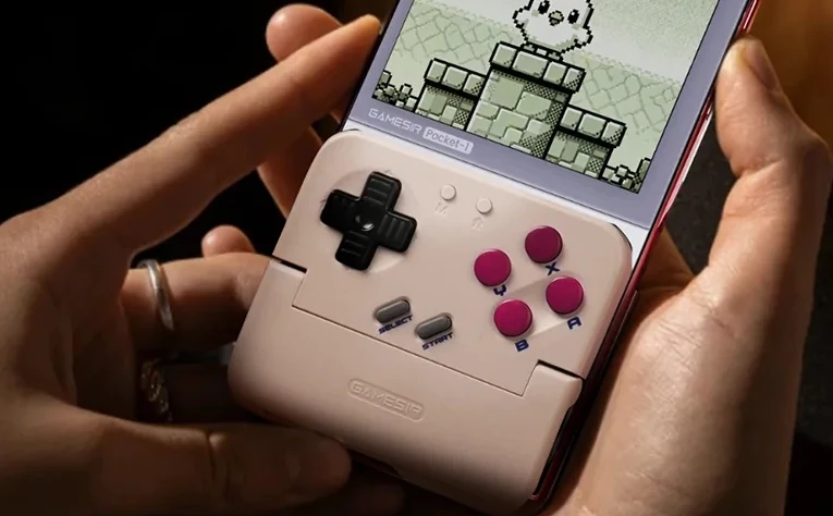 GameSir Pocket Taco Ręce trzymające smartfon wyposażony w zamocowany kontroler przypominający klasyczną konsolę do gier, na ekranie widoczna retro gra platformowa.