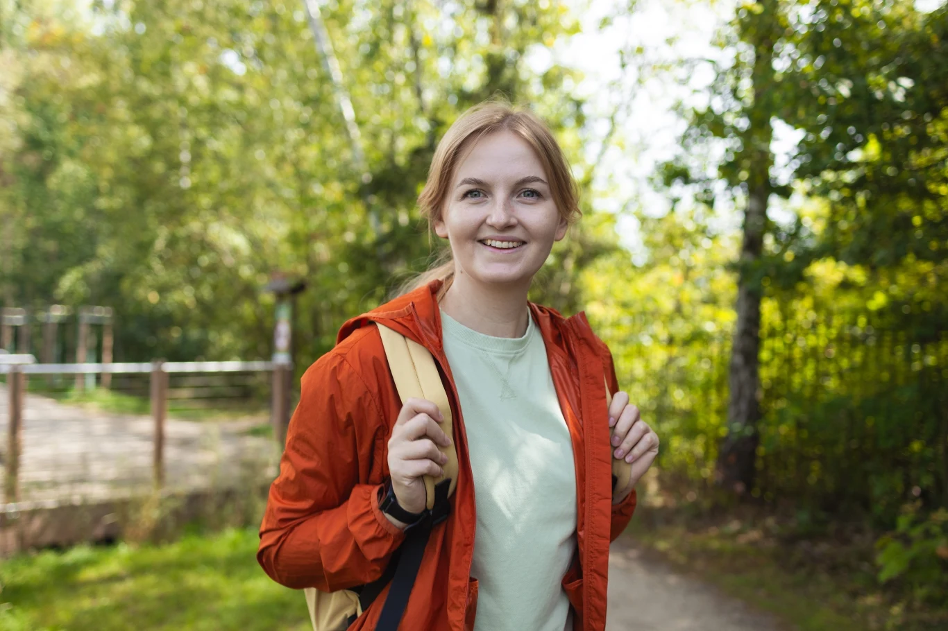 Kampinoski Park Narodowy to idealny pomysł na weekendową wycieczkę Kobieta w pomarańczowej kurtce i z plecakiem spaceruje ścieżką w lesie Kampinoskiego Parku Narodowego.