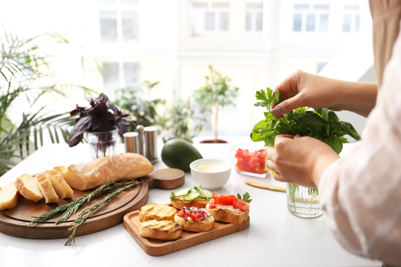 Śniadanie bogate w białko to dobry początek dnia i długotrwałe uczucie sytości. Po jakie produkty warto sięgać? Produkty bogate w białko wyłożone na stole, kobieta przygotowująca sycące śniadanie.