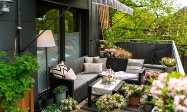 Mały balkon z meblami z technorattanu, poduszkami i kwiatami w doniczkach
