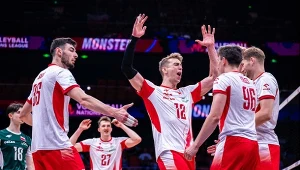 Grupa polskich siatkarzy w biało-czerwonych strojach celebruje zdobyty punkt podczas meczu na hali sportowej.