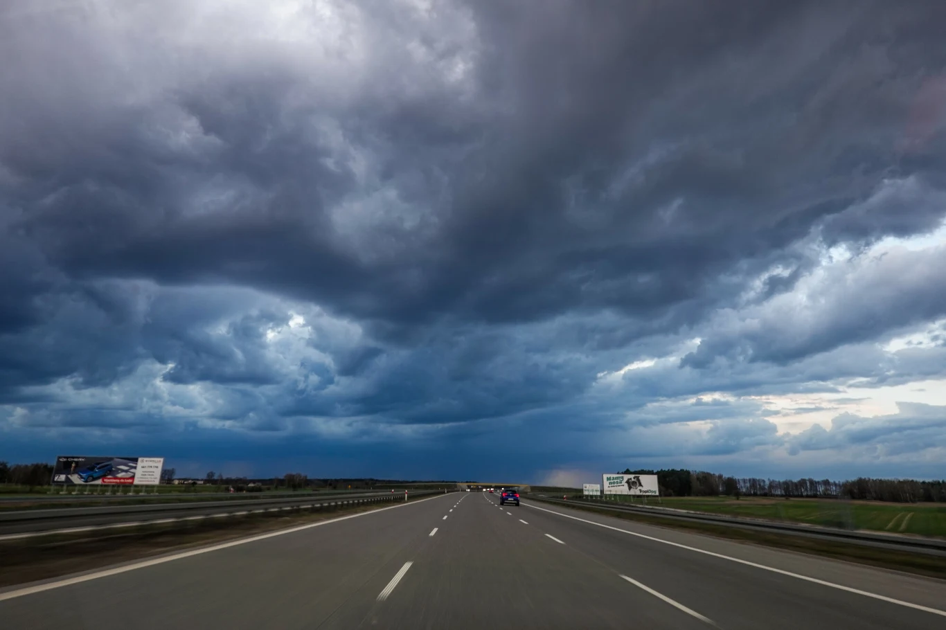 Alert RCB dla całej Polski. Burze, ulewy i upały jednocześnie Pusta autostrada w Polsce pod ciemnymi, burzowymi chmurami, zapowiadającymi silne załamanie pogody.