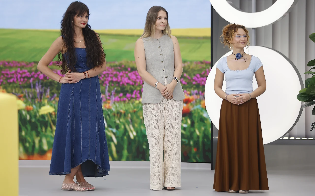 Trzy kobiety stojące obok siebie, każda w odmiennym stylu: jedna w niebieskiej sukience bez rękawów, druga w jasnym, eleganckim bezrękawniku i koronkowych spodniach, trzecia w białej bluzce z dużą biżuterią na szyi oraz szerokiej, brązowej spódnicy; w ...
