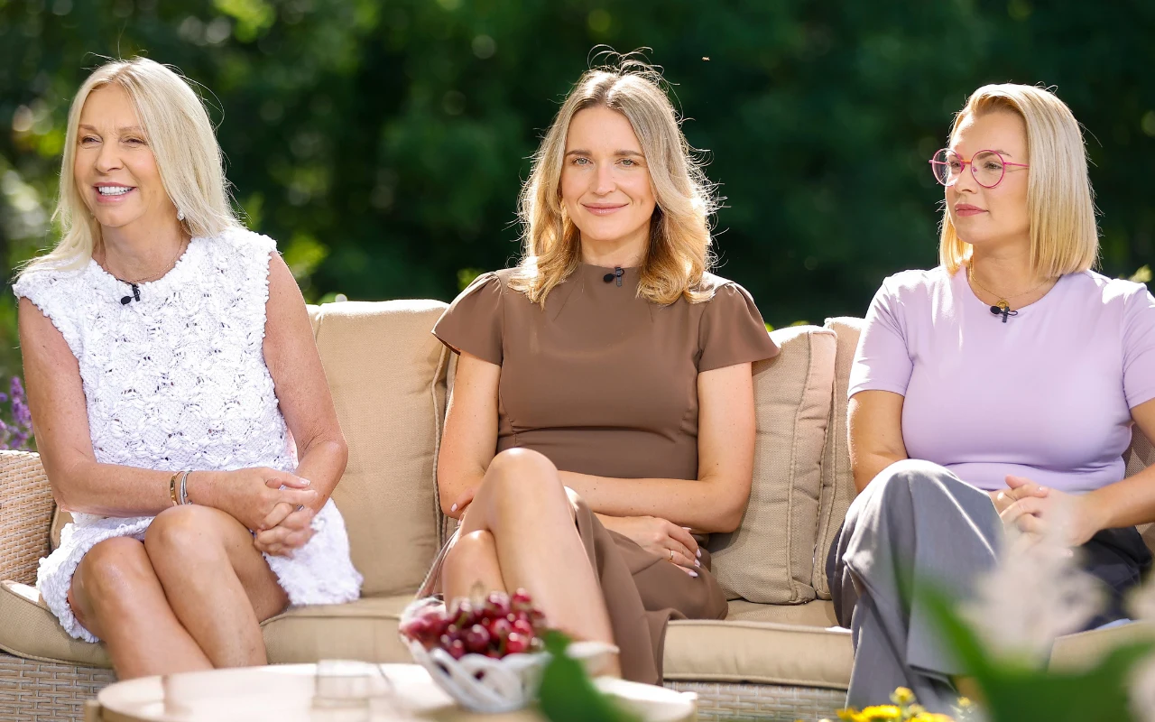 Mariola Bojarska-Ferenc, Agata Stola, Katarzyna von Engel Trzy kobiety siedzące na beżowej sofie na zewnątrz, ubrane w jasne letnie ubrania, każda z nich ma mikrofon przypięty do ubrania, na pierwszym planie misa z owocami.