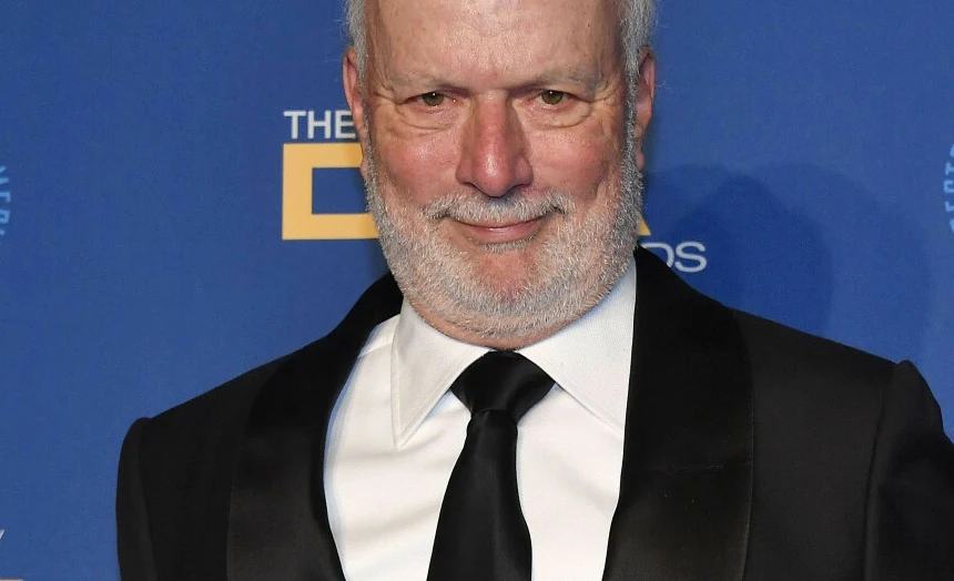 James Burrows James Burrows w smokingu na tle ścianki z logotypami.