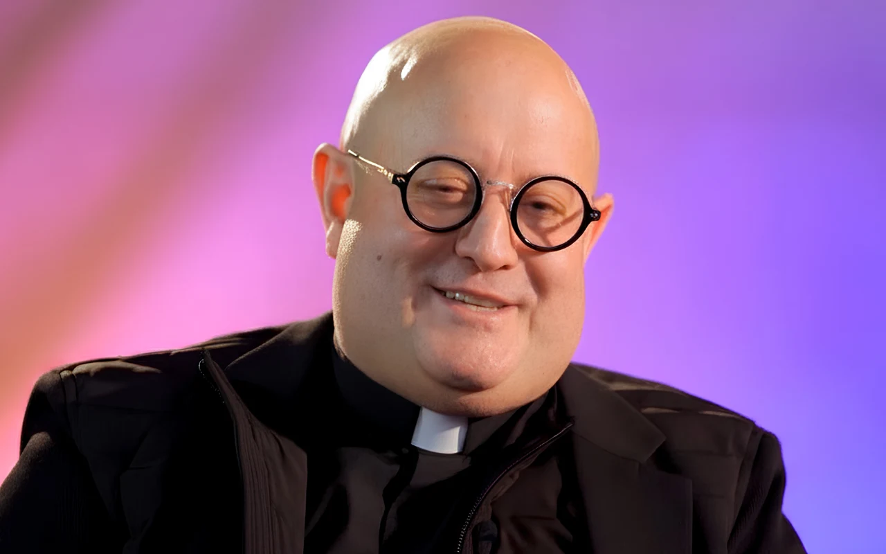 Padre Guilherme w wywiadzie Kamili Ryciak Padre Guilherme w czarnej marynarce, koszuli i koloratce na kolorowym tle