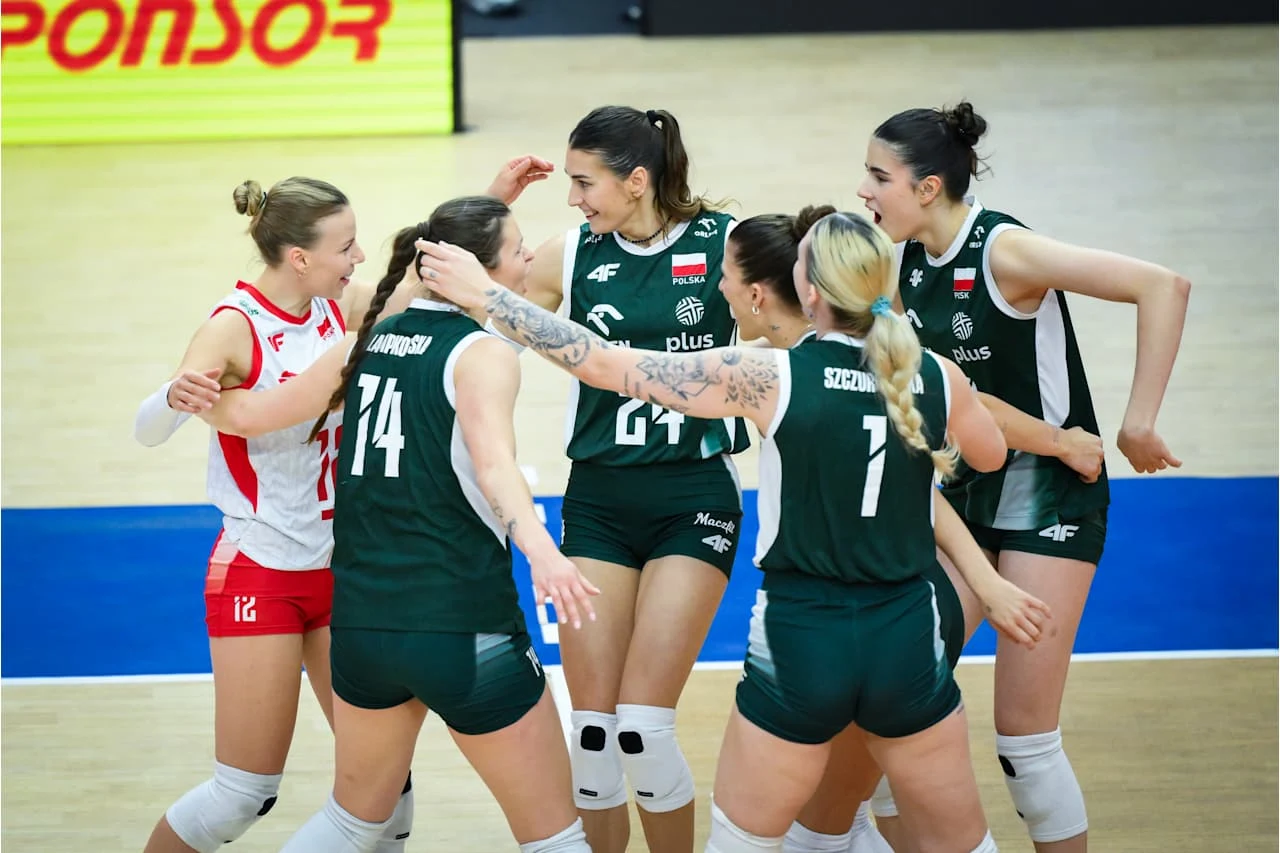 Siatkarki reprezentacji Polski Grupa siatkarek w zielonych strojach świętuje punkt, otaczając uśmiechniętą zawodniczkę w biało-czerwonym stroju; wszystkie stoją na parkiecie sportowej hali.