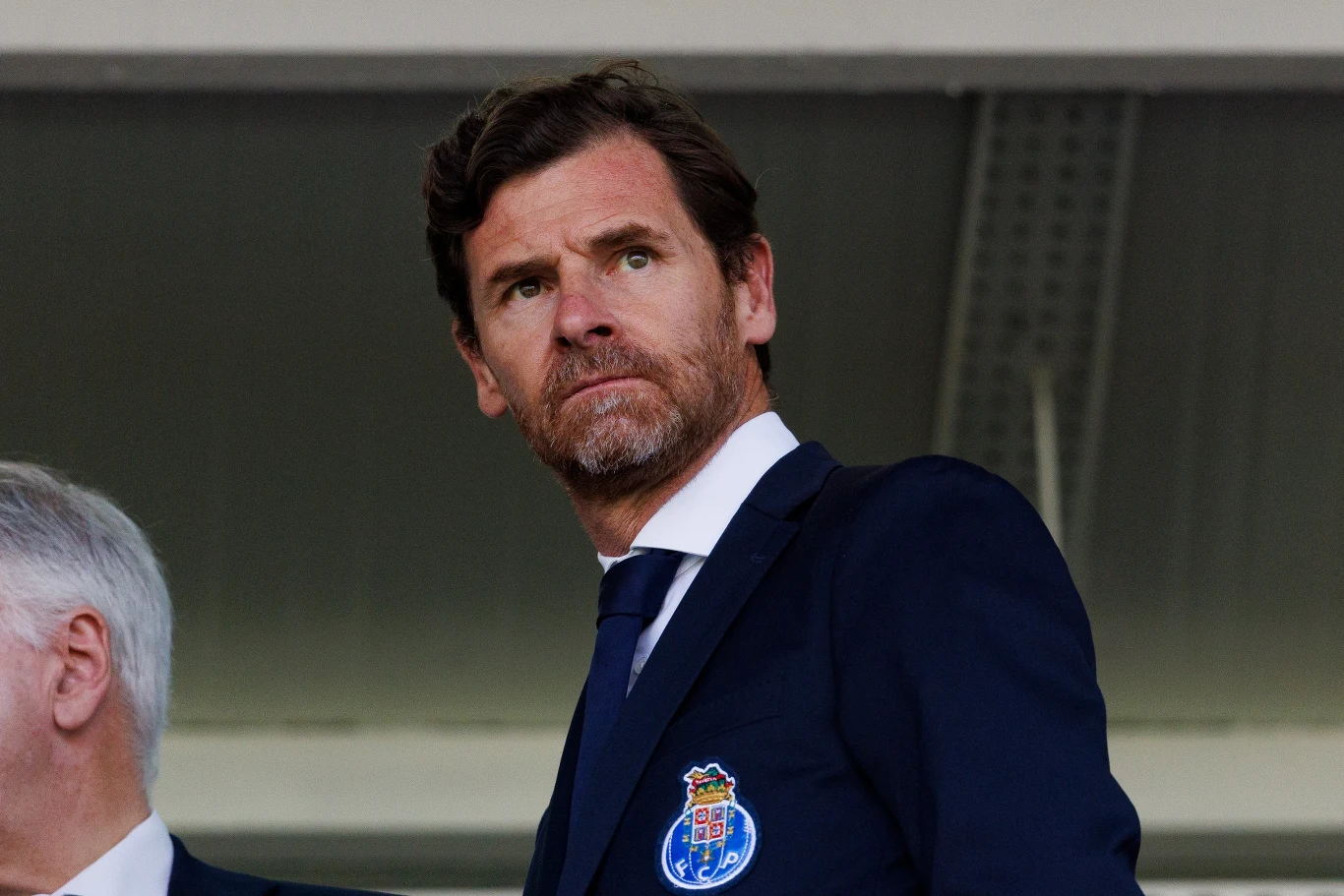 Andre Villasa-Boasa Mężczyzna w garniturze z przypinką FC Porto na piersi, patrzący w stronę boiska.