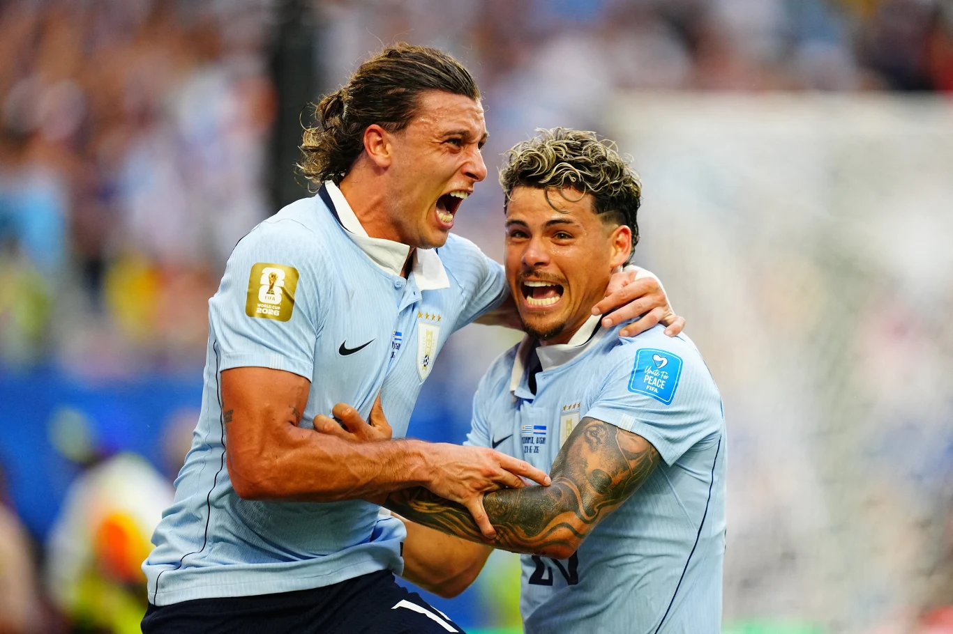 Agustin Canobbio (z lewej) i Maximiliano Araujo fetują bramkę na 2:1 dla Urugwaju Dwóch piłkarzy w błękitnych koszulkach entuzjastycznie obejmuje się i krzyczy z radości po zdobyciu gola na boisku podczas meczu.