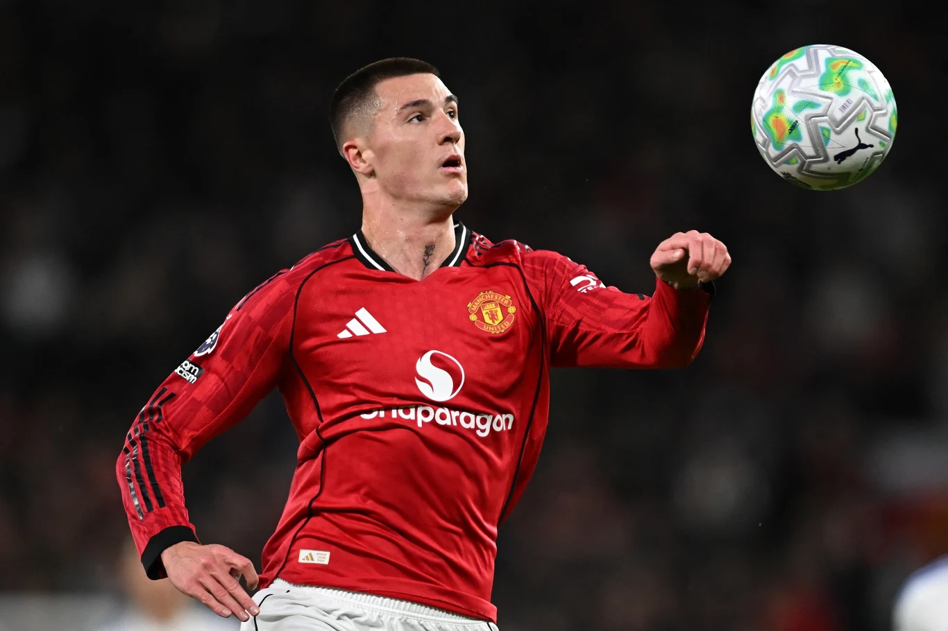 Piłkarz Manchesteru United w czerwonej koszulce skupiony na opanowaniu lecącej piłki w trakcie meczu.