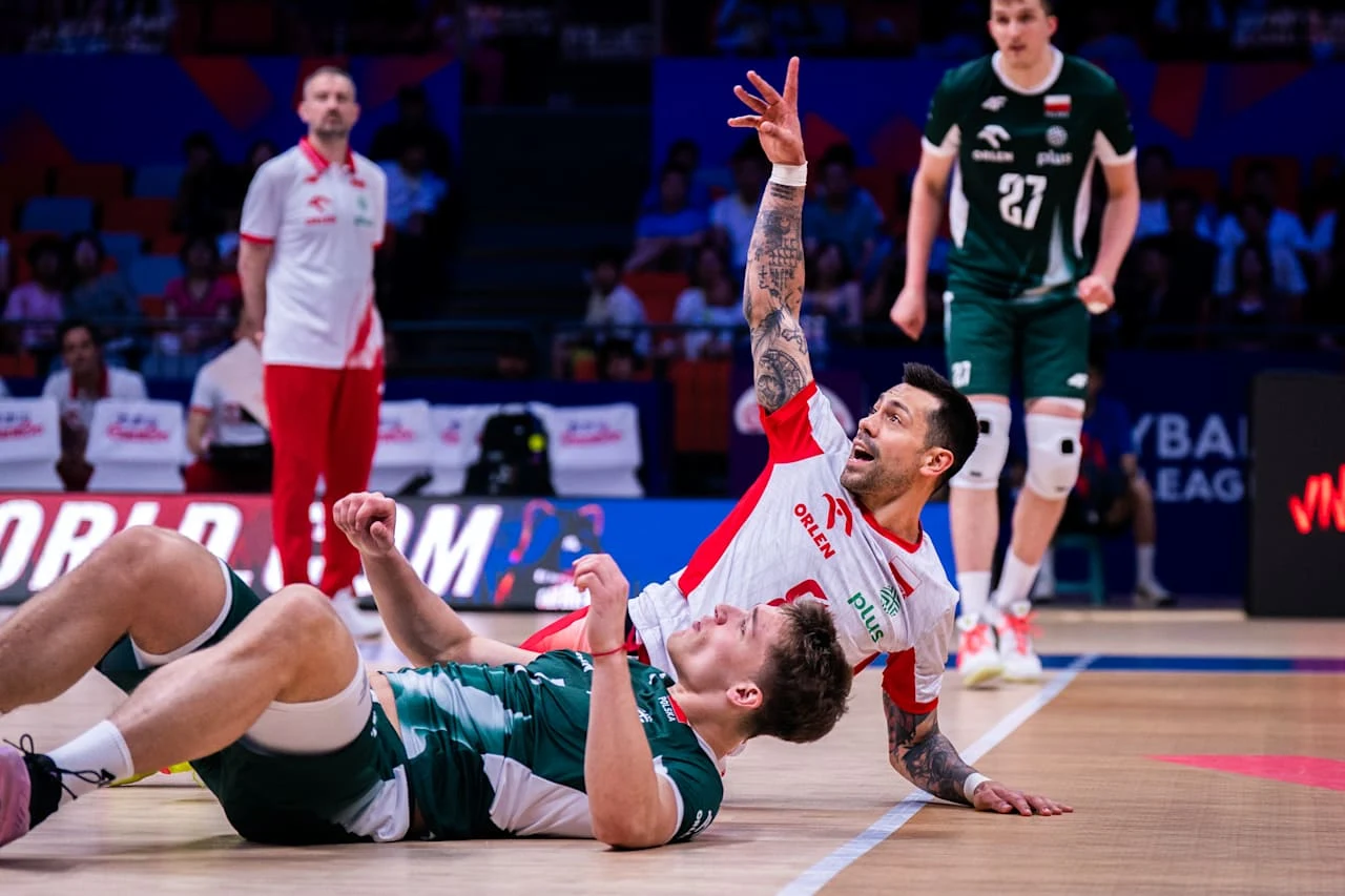Mateusz Czunkiewicz w meczu reprezentacji Polski Dwaj siatkarze leżący na parkiecie podczas dynamicznej akcji, jeden z nich z uniesioną ręką, w tle dwaj zawodnicy stojący na boisku.
