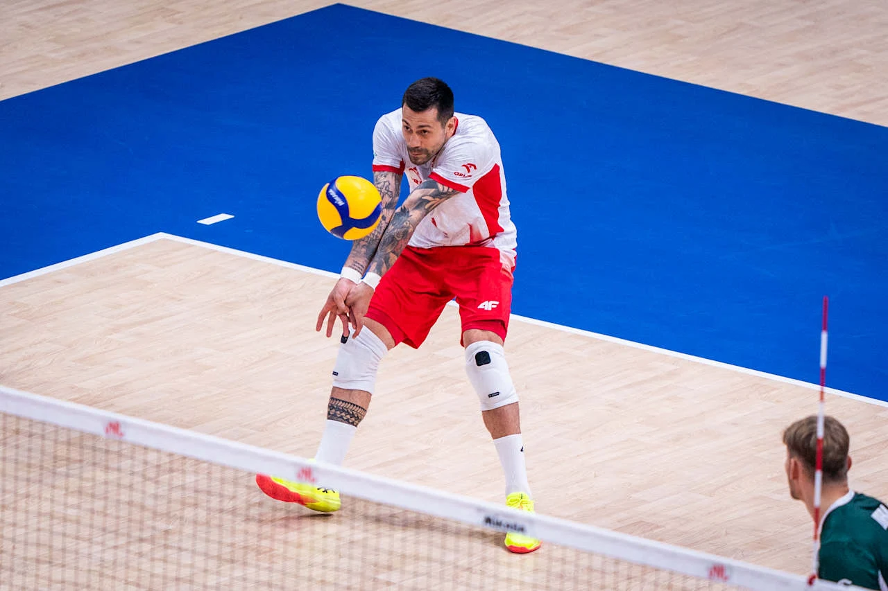 Mateusz Czunkiewicz Polski siatkarz w biało-czerwonym stroju odbijający piłkę sposobem dolnym na hali podczas meczu.