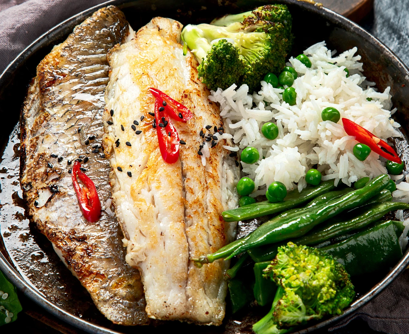 Królewska ryba zbyt rzadko gości w naszym menu. Filety dorady smażone z plasterkami chili i czarnym sezamem, podane z ryżem, groszkiem, brokułami i fasolką szparagową.