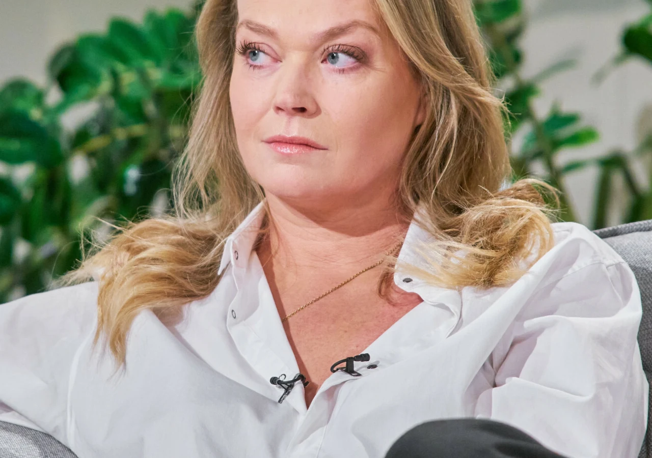 Tamara Arciuch Tamara Arciuch w białej koszuli siedząca na sofie podczas wywiadu, z przypiętym mikrofonem.